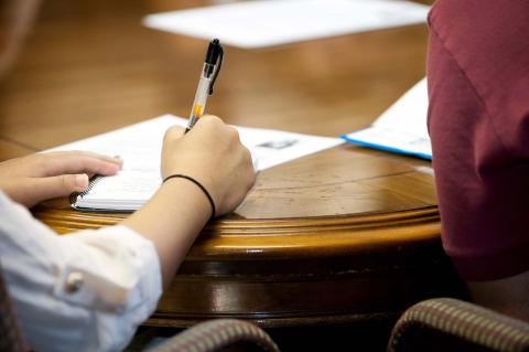 A student taking notes at a table